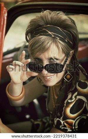 Woman in 70's clothing in vintage car