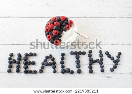 Berries on white background  with the word "healthy" in letters. Served with a  berry protein dessert 