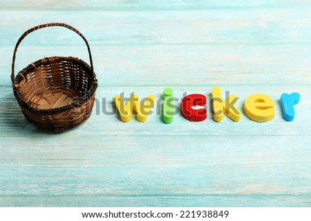 Wicker word formed with colorful letters on wooden background