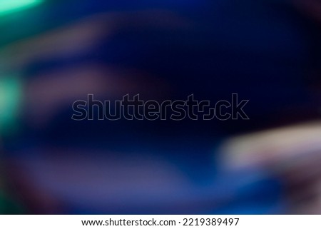 Lens flare overlay. Light leak. Blur glow. Defocused neon blue green orange color flecks texture on dark black abstract copy space background.