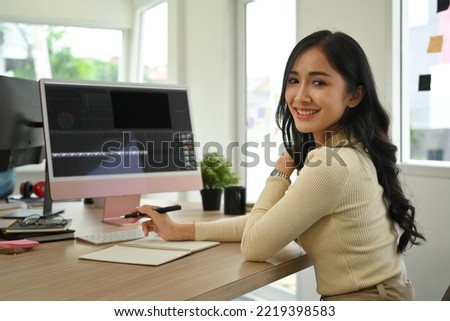 Beautiful young female photo editor sitting in creative workplace and retouching photos on computer