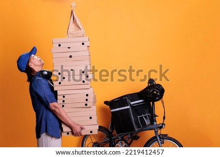 Senior takeaway delivery standing with giving food order and holding pizza boxes, pizzeria service. Restaurant courier transporting takeout food with bike on yellow background. Takeout concept
