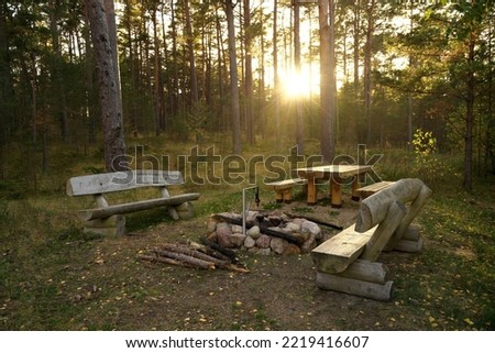 A place to rest on a tourist forest trail. Recreation area in the forest for tourists with a wooden table, benches and a stone fireplace.