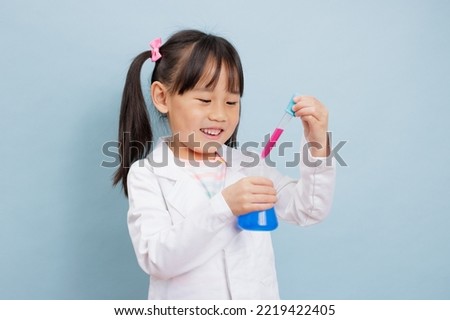 young  girl pretend play scientist role at home against plain background
