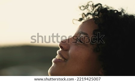 One hopeful young black woman closeup face opening eyes to sky. Religious Spiritual African American female person staring up with HOPE and FAITH