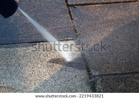 Power cleaning dirty floor, paving slabs with high pressure water jet. Cleaning with high pressure water jet. Cleaning service washing backyard and pavers with pressure water. Royalty-Free Stock Photo #2219433821