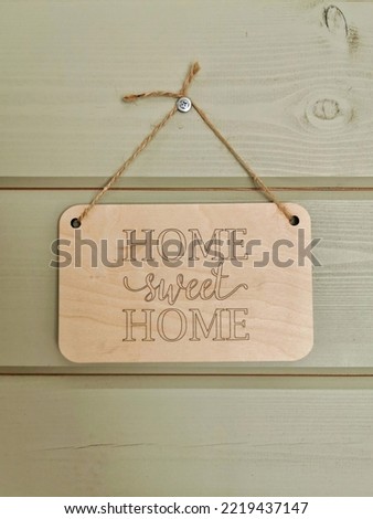 Wooden sweet home sign hanging on the rope on the green wall