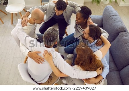 Team of people hugging in office. Group of happy positive smiling diverse international mixed race multiethnic male and female friends sitting in circle holding arms around each other. Support concept Royalty-Free Stock Photo #2219439027