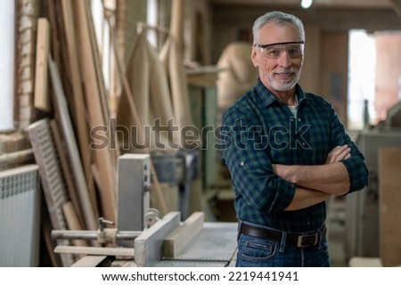 Mature man standing in a workshop and looking confident Royalty-Free Stock Photo #2219441941