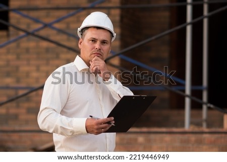 portrait of an engineer with a plan for the construction of an object, an inspector controls the process of building a house. High quality photo