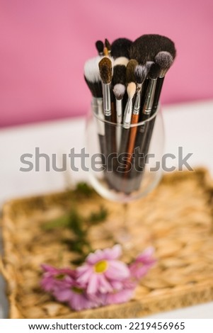 Subject photo, makeup brushes in a glass, on a wicker stand, white and pink background