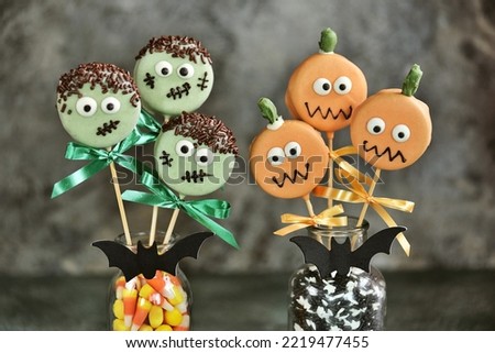 Halloween treat - bright sweet chocolate cakepops pumpkin and monsters on dark background