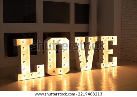 Glowing large letters. Wedding decor. Illuminated Love sign in large letters near window. Love big white letters with led retro bulbs glowing. Word LOVE with a big letters. Inscription is love. 