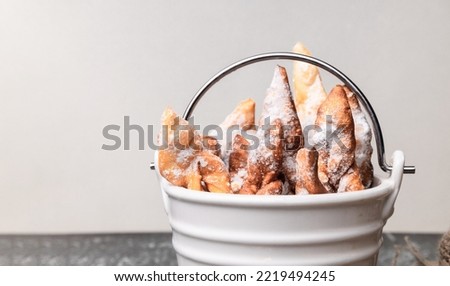 russian traditional dish - Brushwood hvorost. cookies with sugar powder on a white bucket. selective focus Royalty-Free Stock Photo #2219494245