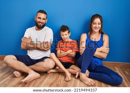 Family of three sitting on the floor at home happy face smiling with crossed arms looking at the camera. positive person. 