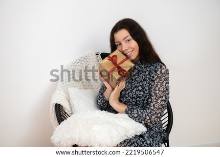 Pretty young woman  brunette with christmas gift box sitting on chair at home