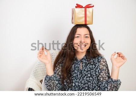 Happy young woman  brunette holding christmas gift box on head over white background
