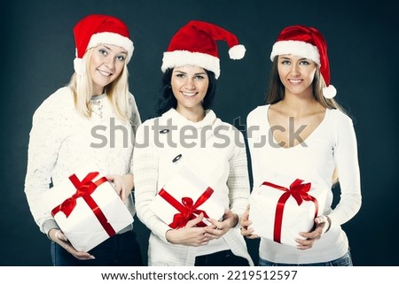 three young women in costume of Santa Claus with Christmas shopping