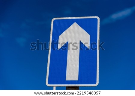 One way sign set against a blue sky	
