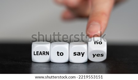 Hand turns dice and changes the expression 'learn to say yes' to 'learn to say no'. Royalty-Free Stock Photo #2219553151
