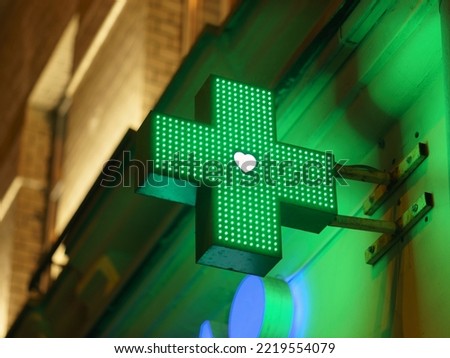 Photography of a green cross, the symbol used for medical intitutions. Symbol is located on the exterior of a building. Moscow city in night 