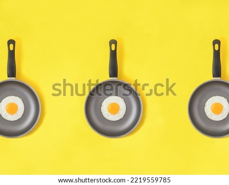 Frying pan with fried egg on the yellow background. Pattern. Flat lay. Top view.