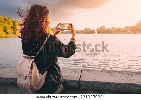 Travel blogger takes photos on the camera of smartphone of the Aasee lake in Munster, Germany
