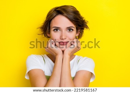 Photo of pretty cute nice glad girl with bob hairstyle dressed white t-shirt arms on cheekbones isolated on yellow color background