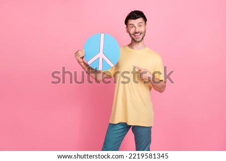 Photo of positive cheerful man dressed yellow clothes arm hold hippie sign dream harmony peace isolated on pink color background