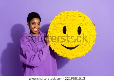 Photo of positive charming transgender person hold emoji smiley pinata wear hoodie isolated violet color background Royalty-Free Stock Photo #2219581513