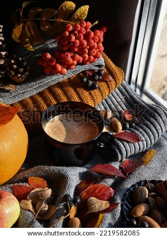 Autumn still life with a cup of coffee, autumn leaves, pumpkin. Evening time in the comfort of home.