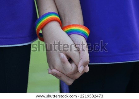 LGBT Asian youth couple wearing rainbow wristbands held together to show their love. Pride of being LGBT. soft and selective focus.                              