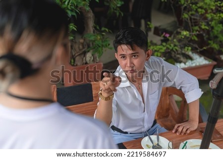 An arrogant young man complains about poor service or terrible food to a waitress. A rude and condescending customer belittling and criticizing the restaurant staff. Royalty-Free Stock Photo #2219584697