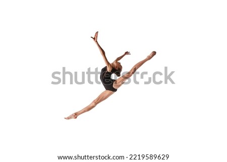 Twine in jump. Emotions in motion. Portrait of junior gymnast in black sport swimsuit doing gymnastics excercises isolated over white background. Sport, skills, achievements