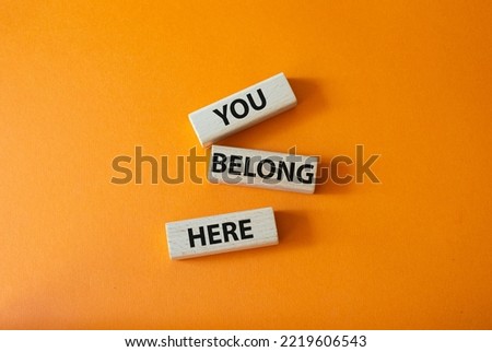 You belong here symbol. Wooden blocks with words You belong here. Beautiful orange background. Business and You belong here concept. Copy space.