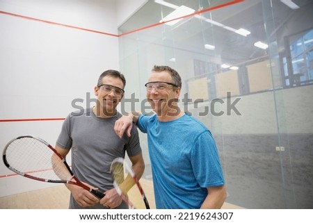 Portrait of smiling men holding squash rackets