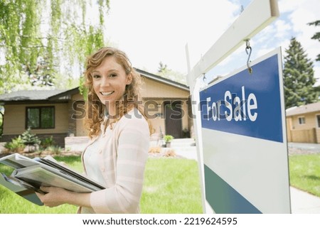 Portrait of realtor next to For Sale sign