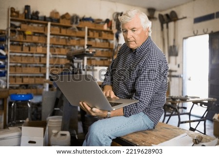 Senior man using laptop in workshop Royalty-Free Stock Photo #2219628903