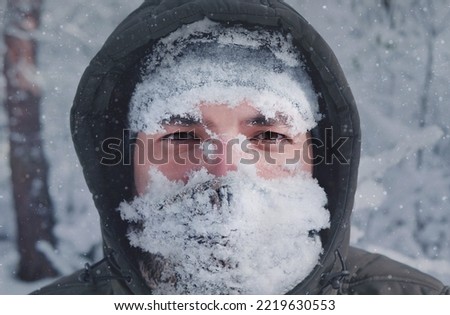 Man's face in the snow against the backdrop of a snowfall. Man in snow storm close up, snowy frosty winter Royalty-Free Stock Photo #2219630553