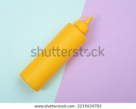 Yellow plastic bottle of mustard on a pastel background