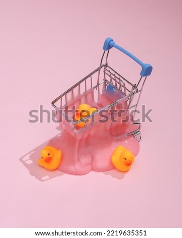 Creative summer layout, mini shopping trolley with slime and rubber ducks on pink background with shadow. Visual trend. Fresh idea. Concept pop