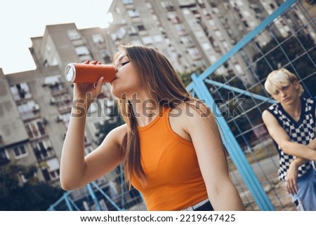 A teenage girl drinks soda on a street. Royalty-Free Stock Photo #2219647425