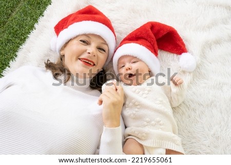 Our first christmas together - happy mother and baby girl in santa hats