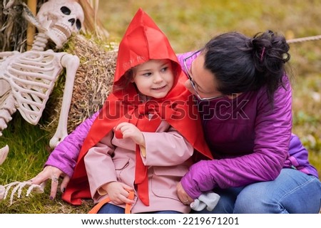 Young girl in a halloween red riding hood costume taking pictures at the fair