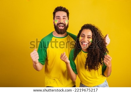 couple of brazil soccer supporters, dressed in the colors of the nation, black woman, caucasian man. Twisting and vibrating. Royalty-Free Stock Photo #2219675217