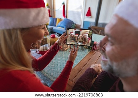 Senior caucasian couple having christmas video call with caucasian family. Communication technology and christmas, digital composite image.