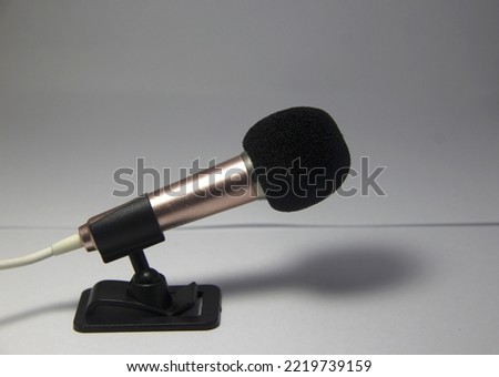 Small mini wired metal mic with microphone desk stand on simple background.