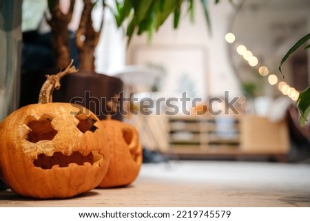  Creepy Pumpkins with the eyes of crosses stand in a light interior on the floor. Halloween concept.