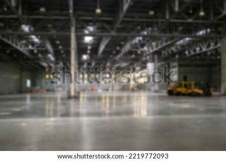 Warehouse interior blurred. Empty warehouse without anyone. Old warehouse interior without shelving. Spacious hangar with metal roof. Storage room with forklift. Rental industrial premises. Art focus