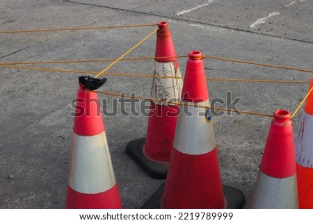a group of traffic cones with white and orange stripes on gray asphalt in a shopping center parking lot